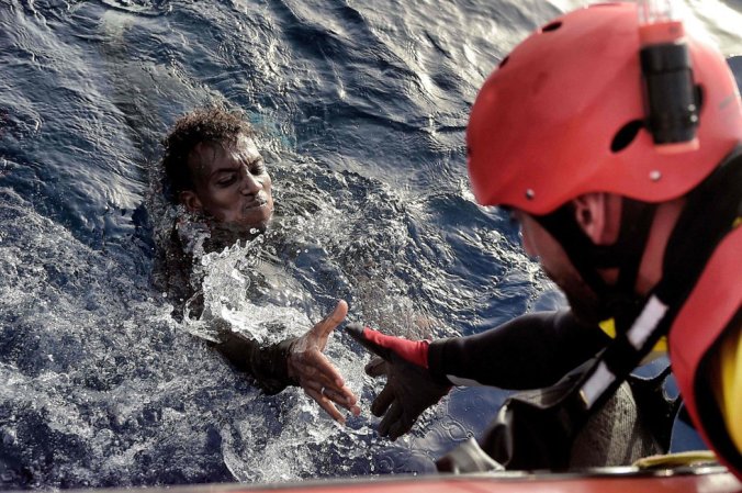 Un hombre es rescatado por un miembro de la ONG Proactiva Open Arms, a 20 millas náuticas de la costa de Libia, el 3 de octubre / Foto: Aris Messinis (AFP)